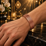 Clarity Code copper bracelet with a staggered leaf pattern, worn on a hand model’s wrist in warm golden light.